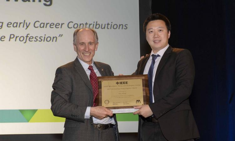 Hua Wang is presented with the 2017 IEEE MTT-S Outstanding Young Engineer Award by Dylan Williams, the president of IEEE MTT-S. 